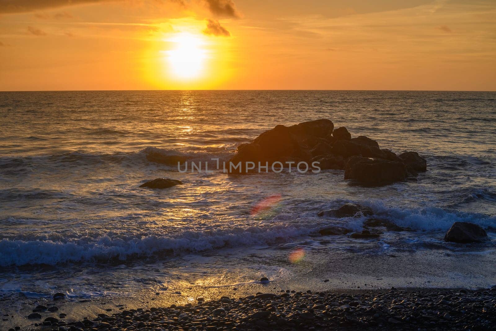 sunset on the sea - A sea wave breaks on a large stone with beautiful white splashes. 2