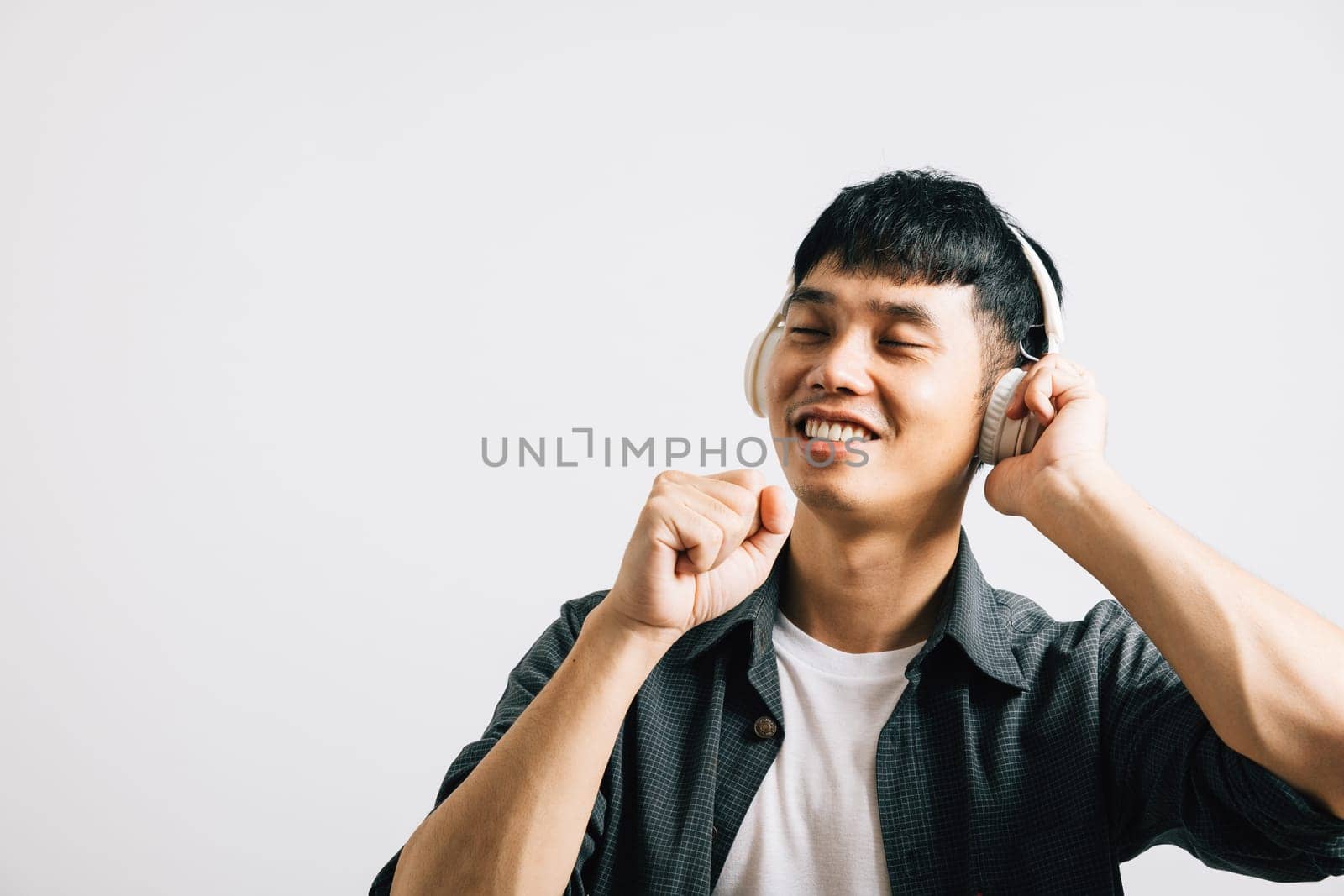 Portrait Asian smiling young man wearing make hands look like holding microphone and singing song studio shot isolated white background, Happy lifestyle men listens to music, happiness and enjoyment