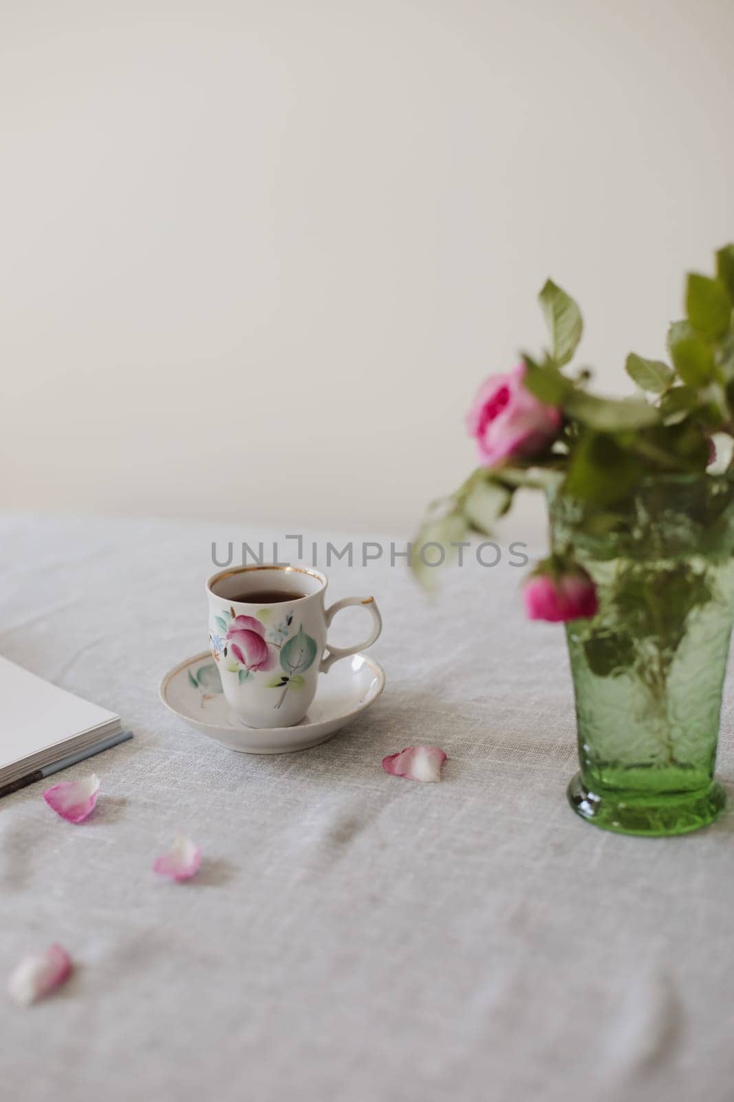 Moody summer still life. Table composition with cup of coffee, tea and beautiful floral bouquet with pink roses.