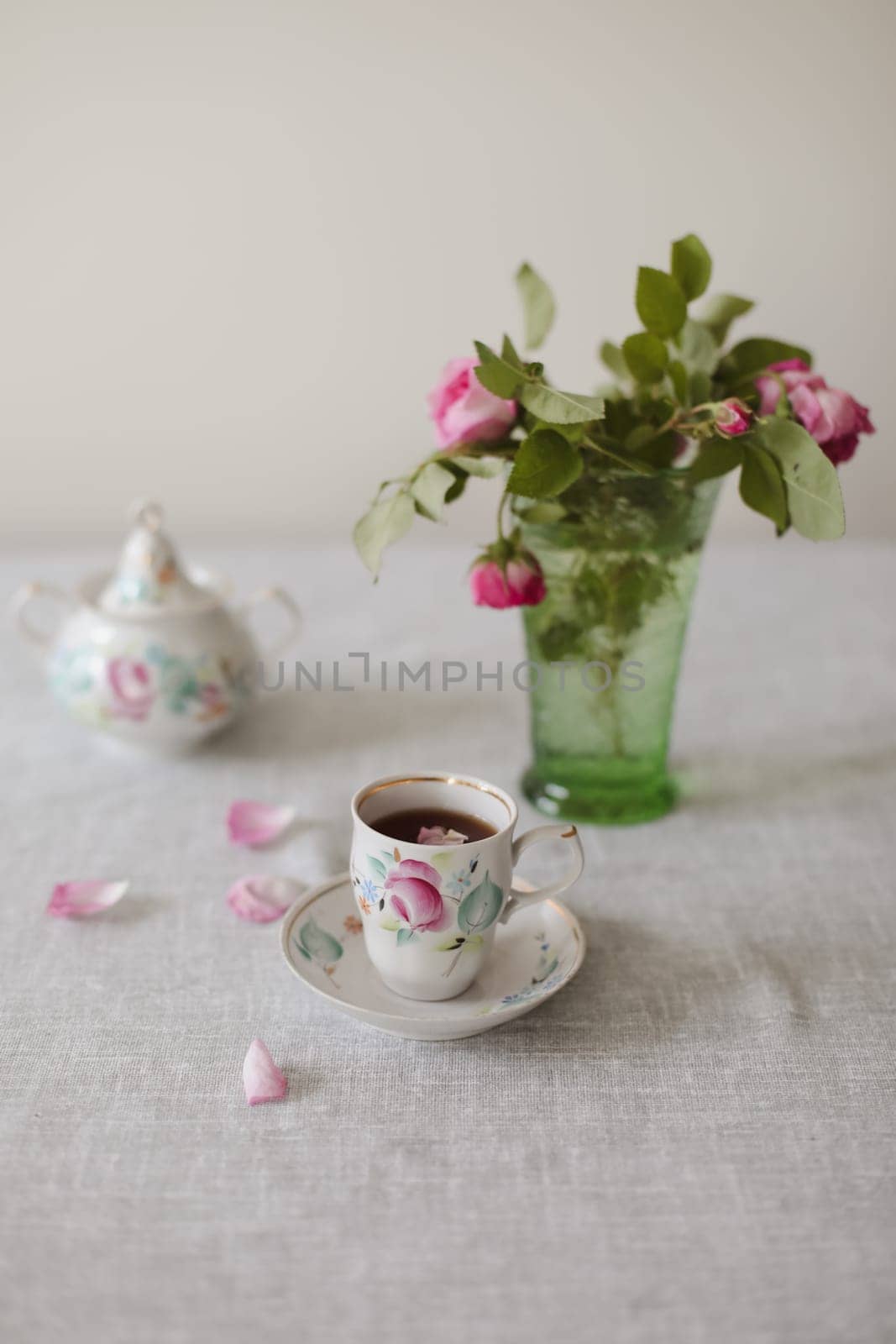 Moody summer still life. Table composition with cup of coffee, tea and beautiful floral bouquet with pink roses.