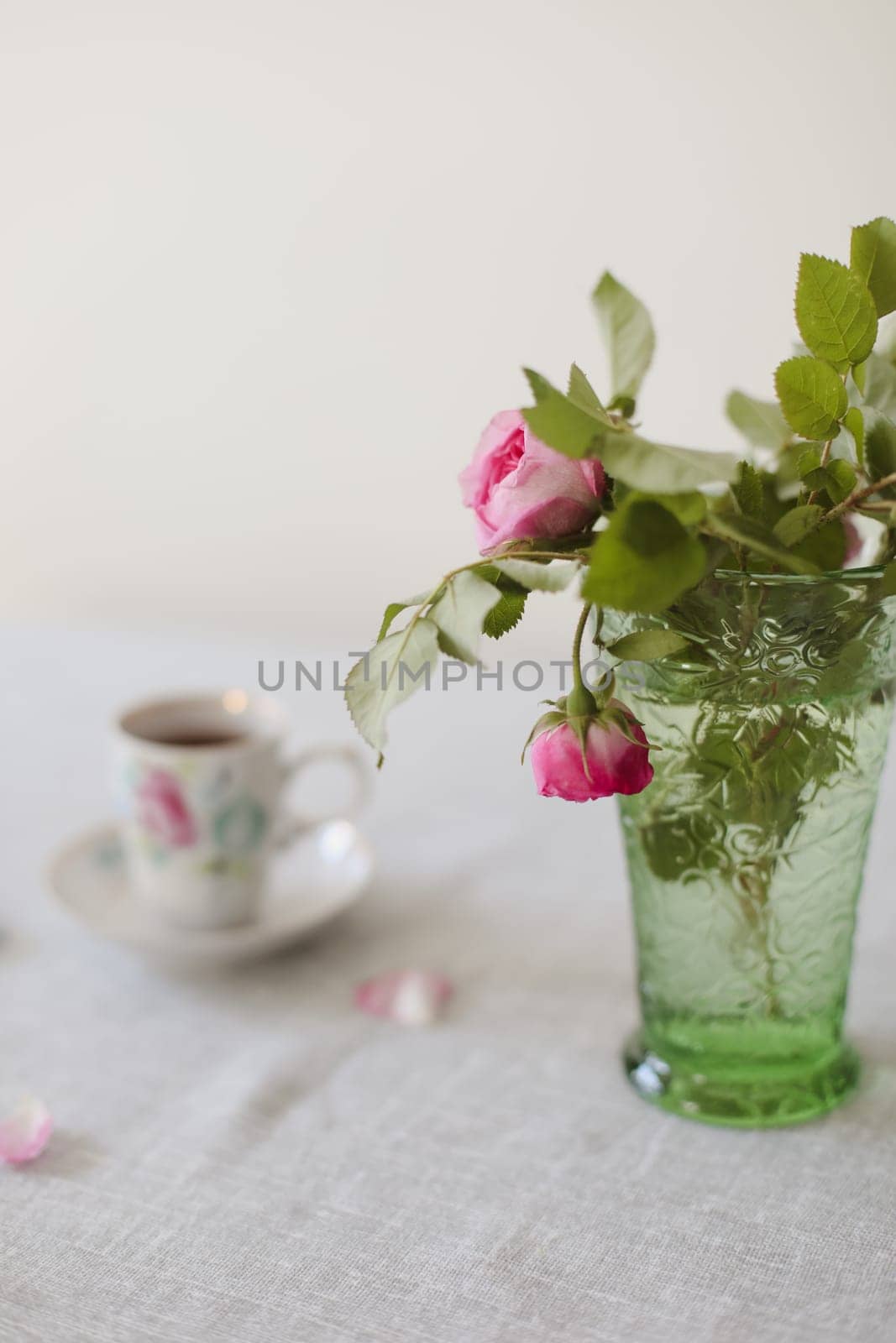 Moody summer still life. Table composition with cup of coffee, tea and beautiful floral bouquet with pink roses.