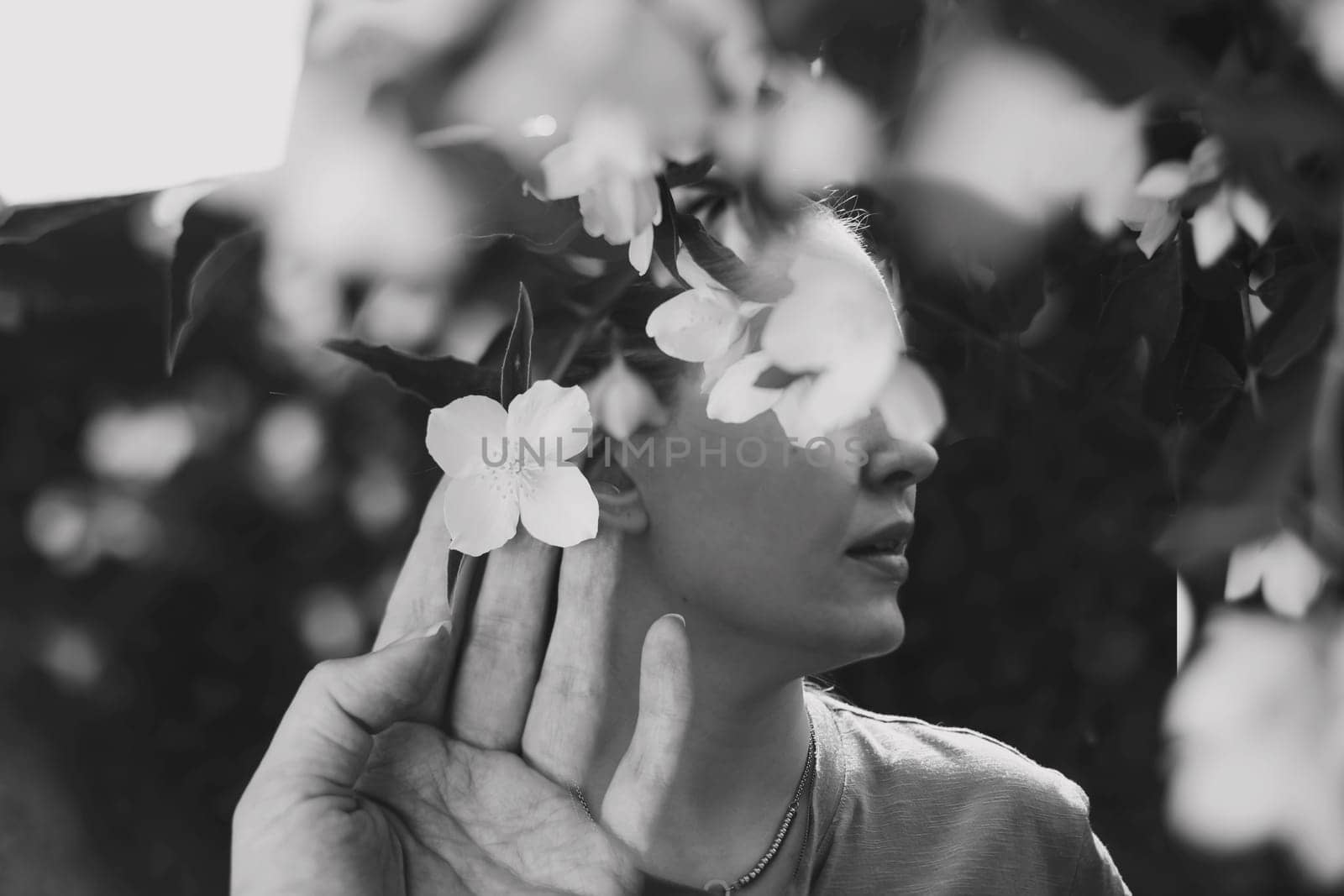 Abstract contemporary art collage black and white portrait of young woman with flowers on face hides her eyes. Creative portrait with Multiple exposure.Young beautiful female model with flowers