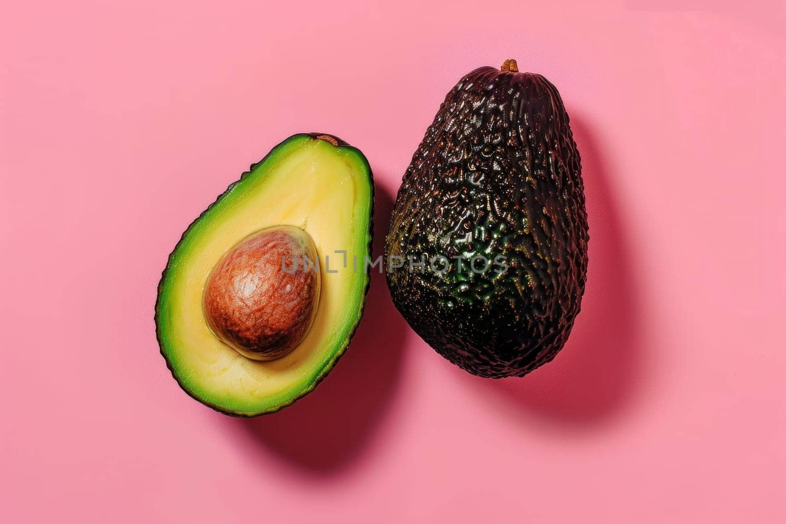 Two ripe avocados on pink background with avocado copy space for food and health concept