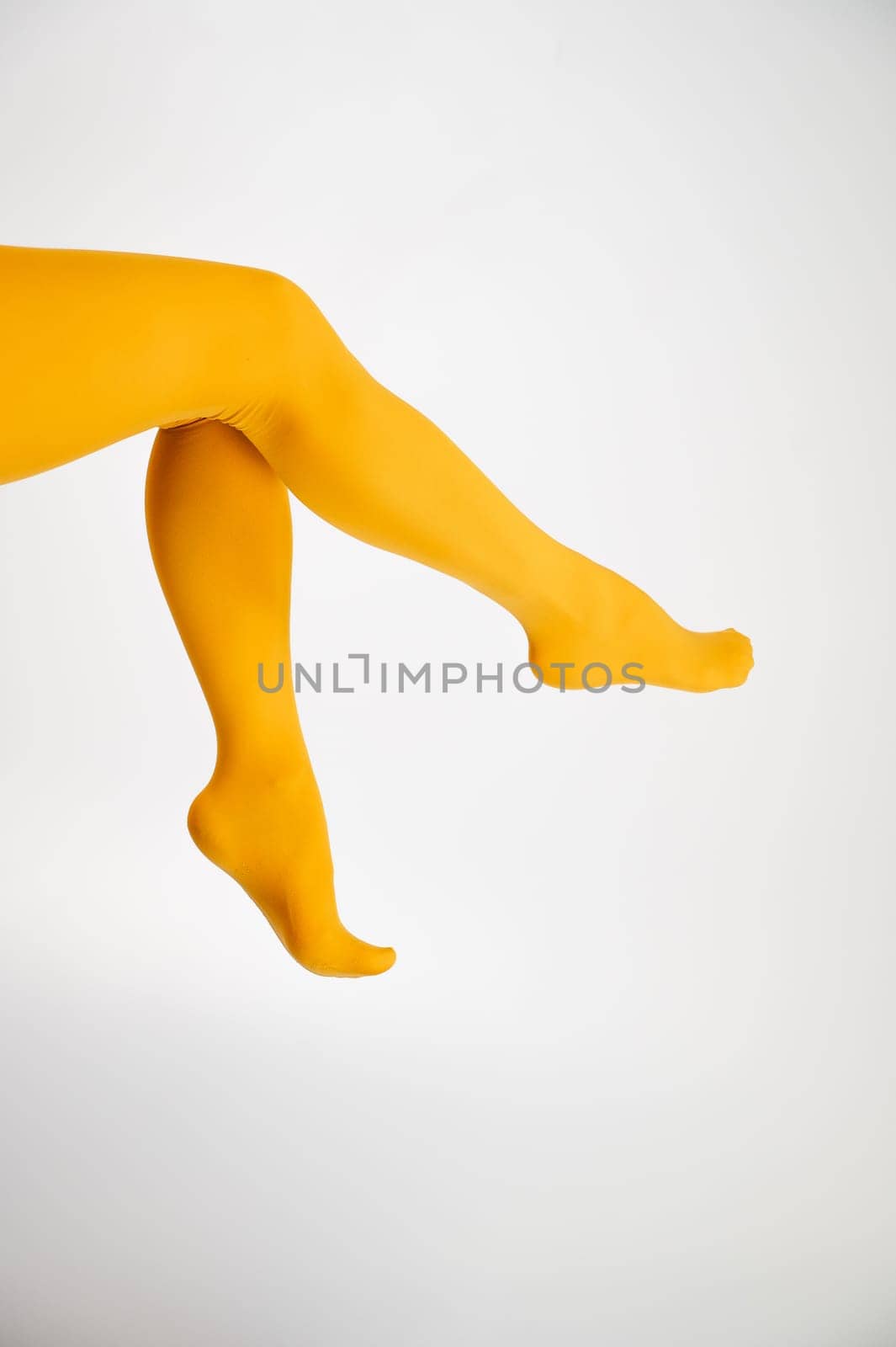 Female legs in ocher tights on a white background. Vertical photo