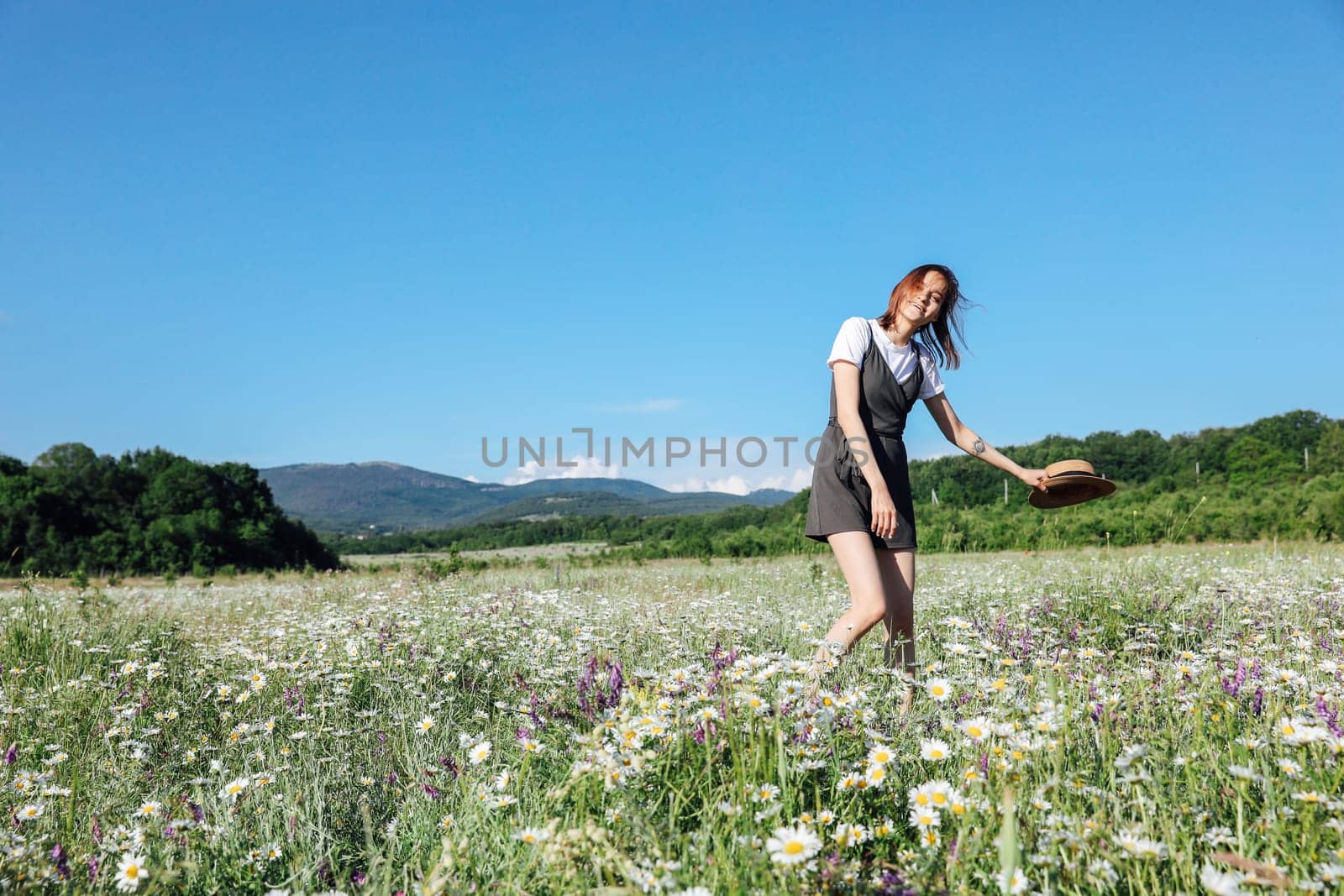 in nature, a woman with a hat runs into a field with daisies flowers by Simakov