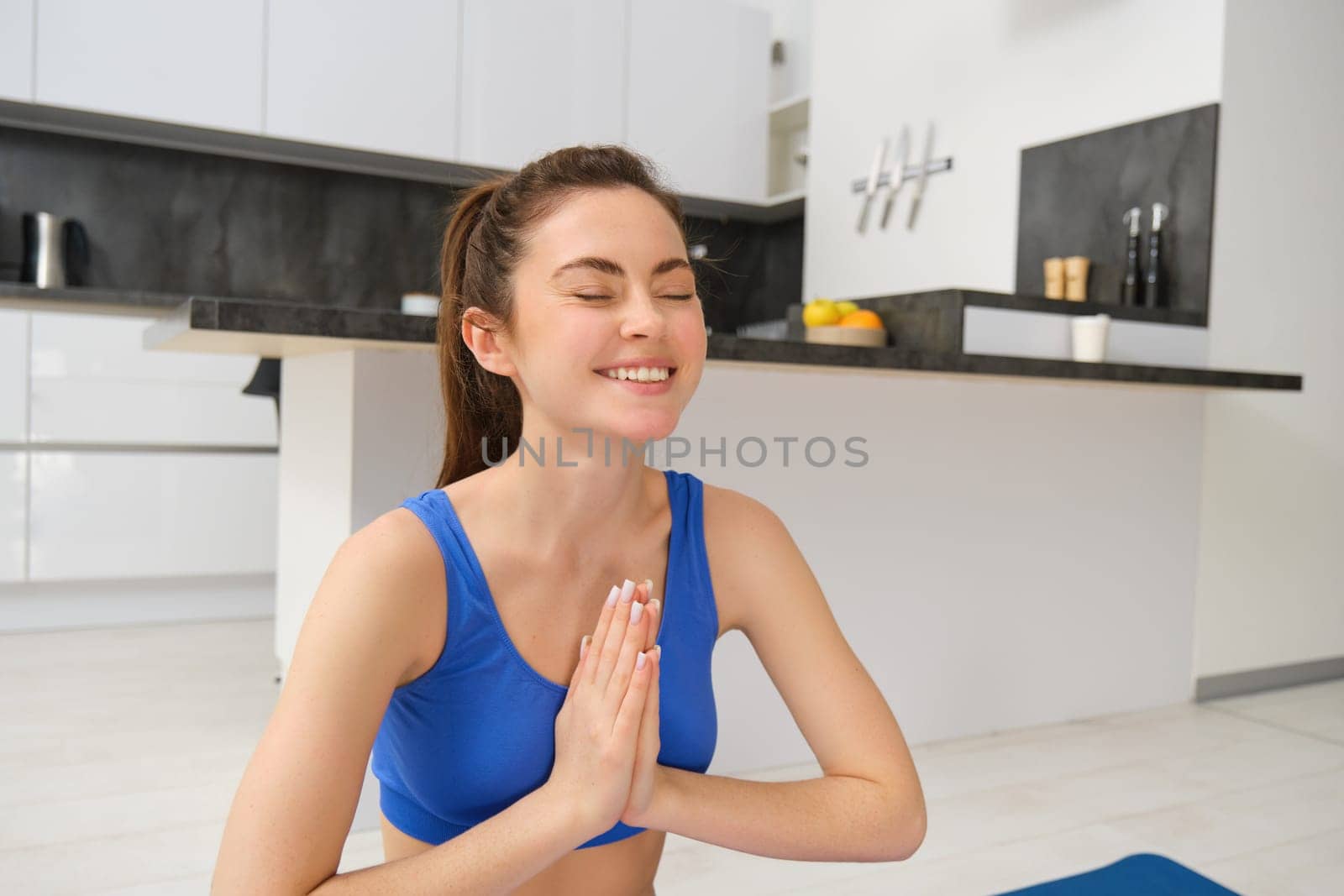Image of beautiful woman doing training, workout from home in living room, practice yoga, sitting on floor and meditating.