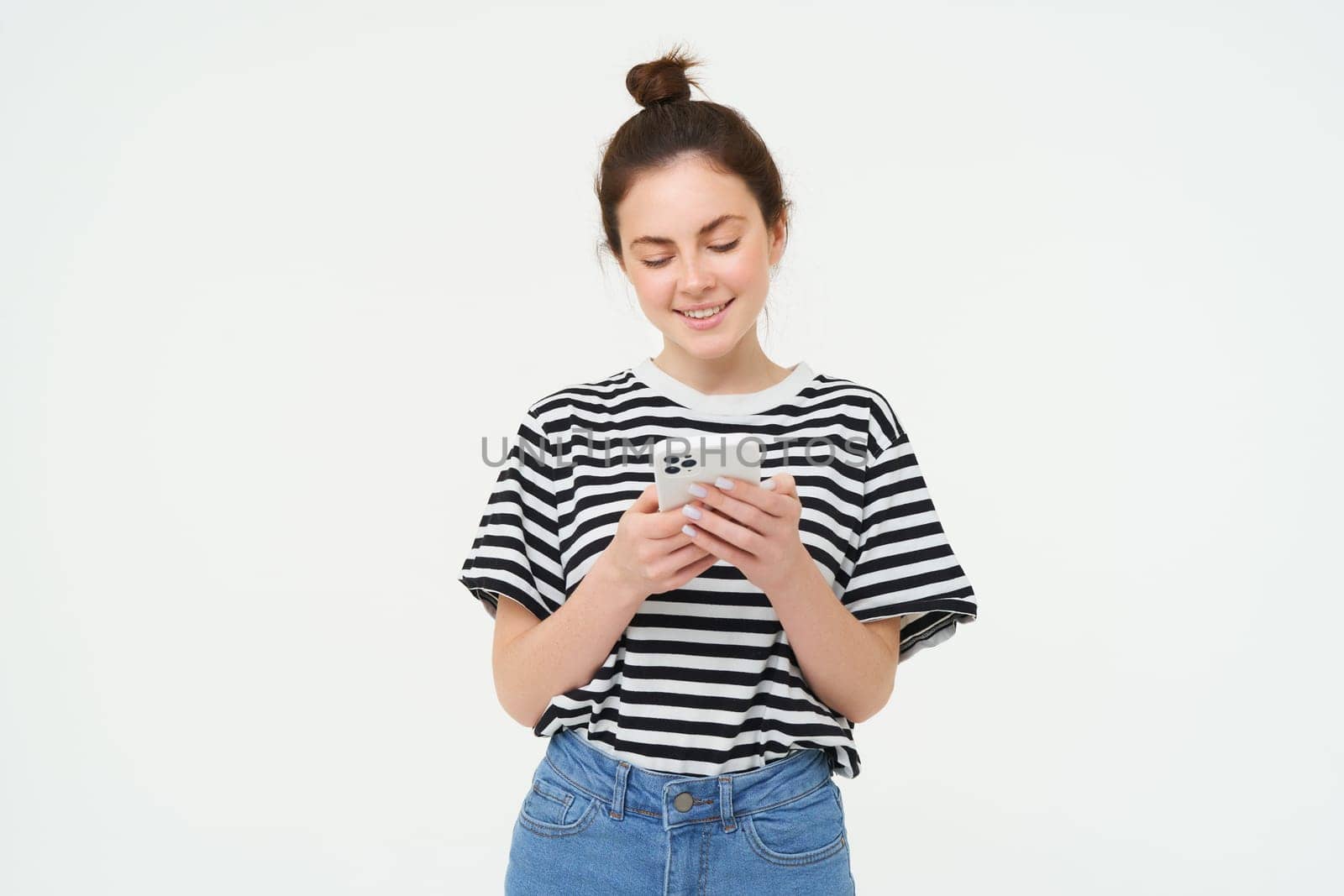 Image of young smiling woman, holding mobile phone, using smartphone application, isolated over white background by Benzoix