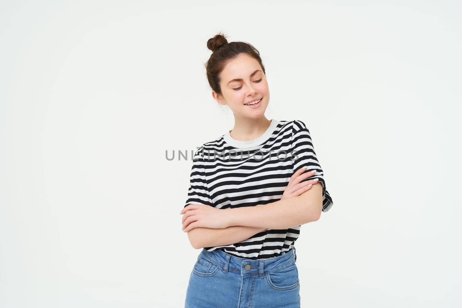 Portrait of attractive, stylish young woman, 25 years old, wearing t-shirt, cross arms against chest and smiling, looking confident, isolated over white background.