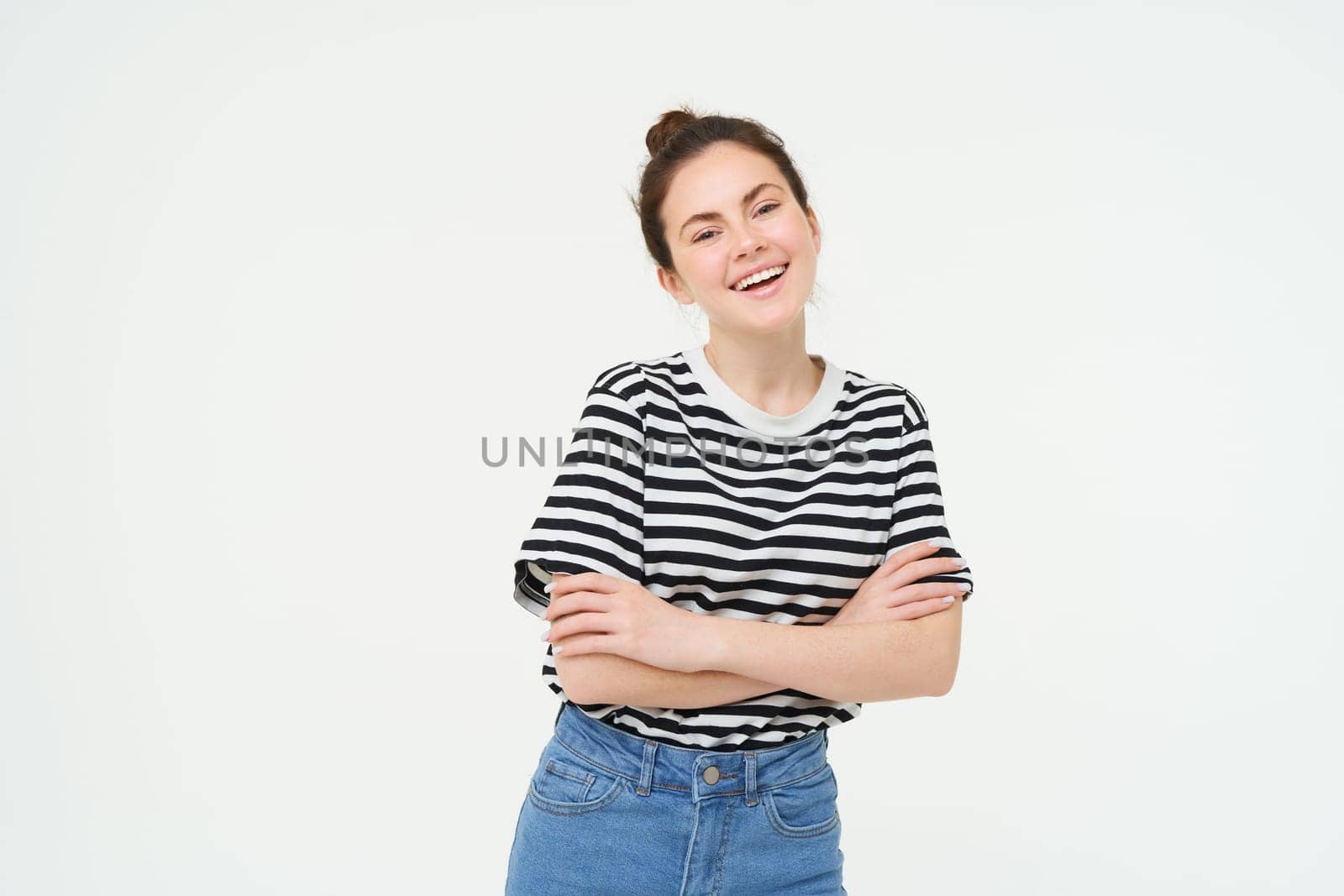 Image of charismatic young woman in striped t-shirt and jeans, looking confident and happy, smiling at camera, candid emotions, white background.