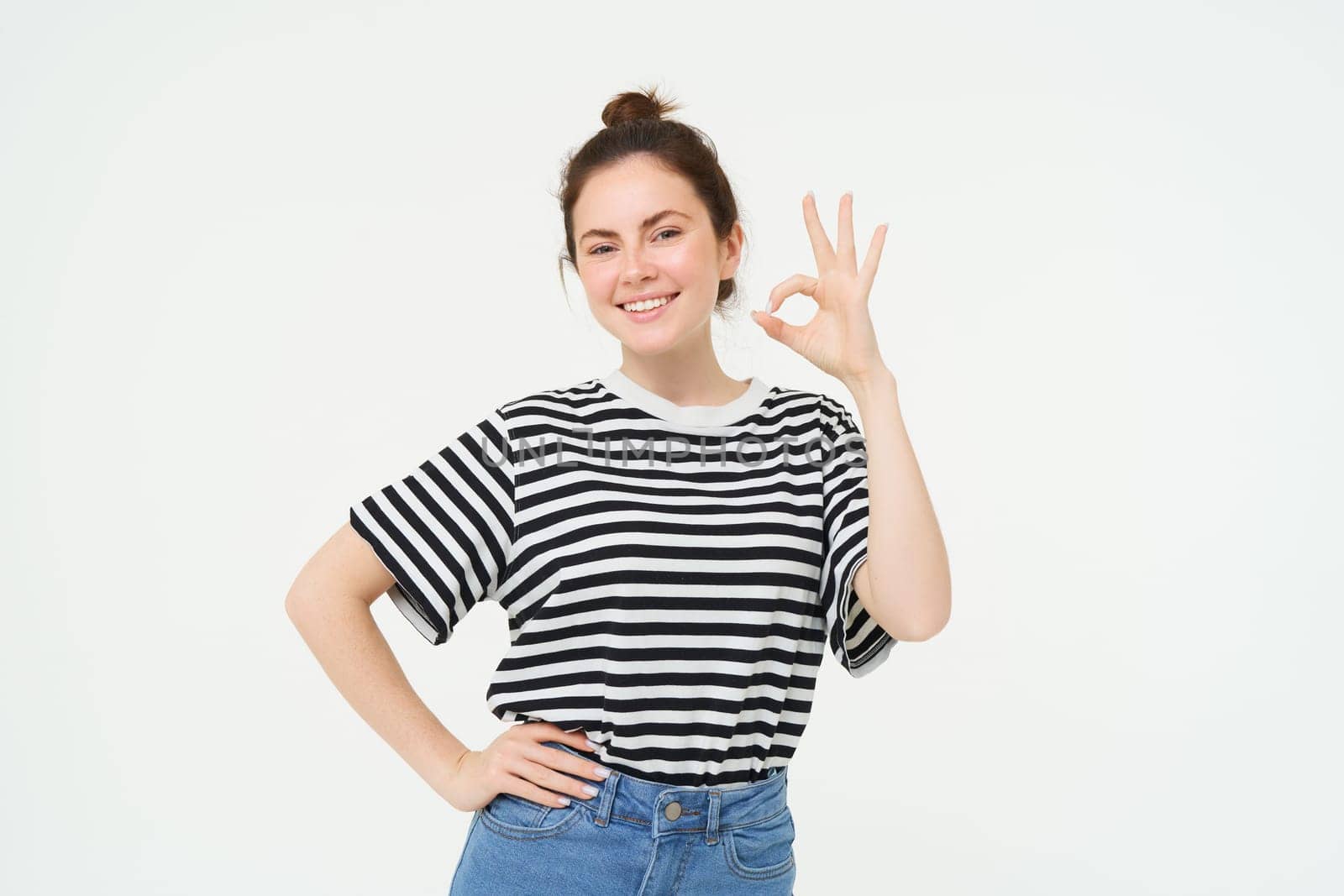 No problem, excellent choice. Smiling, confident young woman, showing okay, ok sign, zero gesture, recommends product, stands over white background by Benzoix