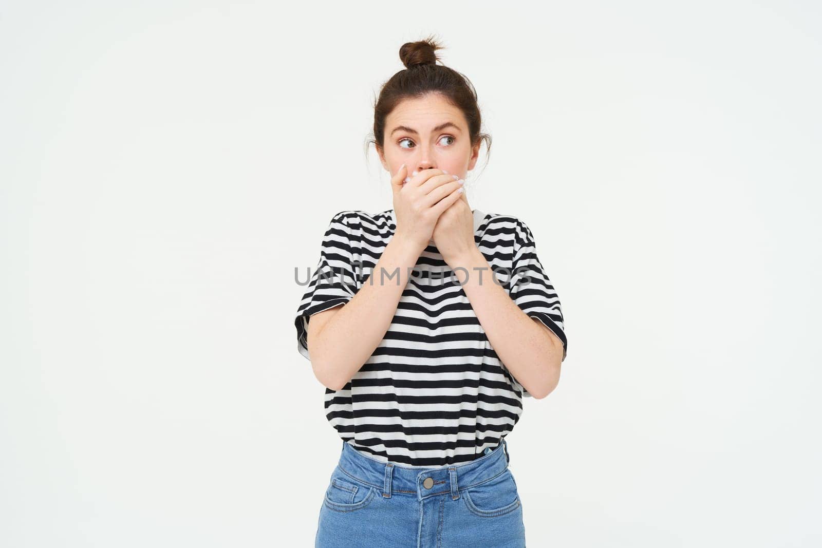 Image of shocked woman, covers her mouth, looks surprised, stands over white background by Benzoix