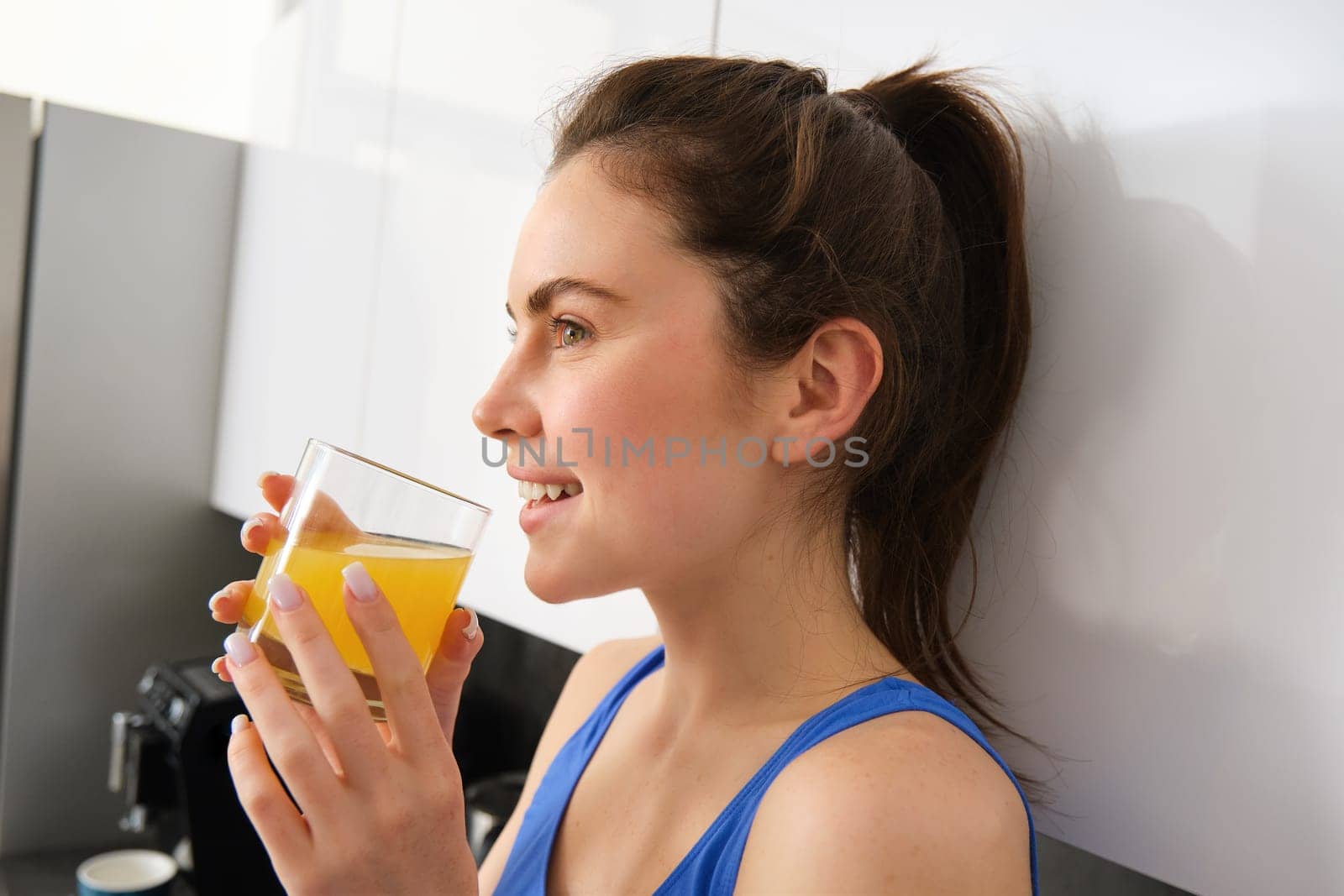 Shot of sporty beautiful woman drinking detox juice in the kitchen at home by Benzoix