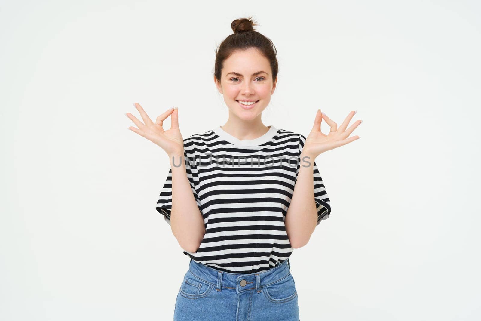 Keep calm and meditate. Young woman relaxing, standing in asana, zen pose, holding hands sideways and meditating, standing over white background.