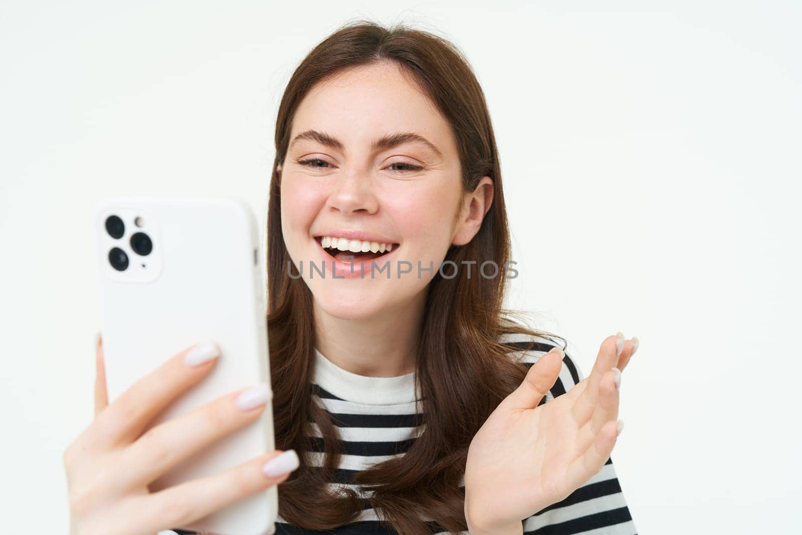 Portrait of woman chats on mobile phone video app, talks at smartphone camera, laughing and looking at telephone.