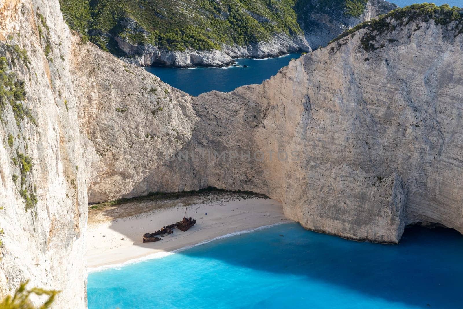 A beautiful view of a deserted beach with a sunken pirate ship washed ashore on a sunny summer day, close-up side view from a cliff.