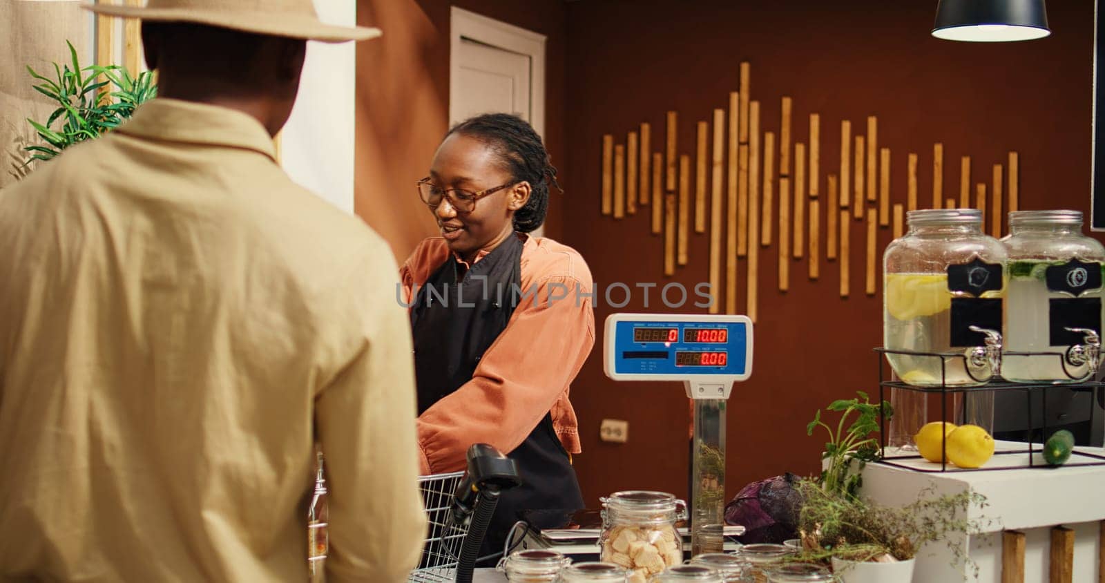 Woman scanning organic goods for client at checkout counter by DCStudio