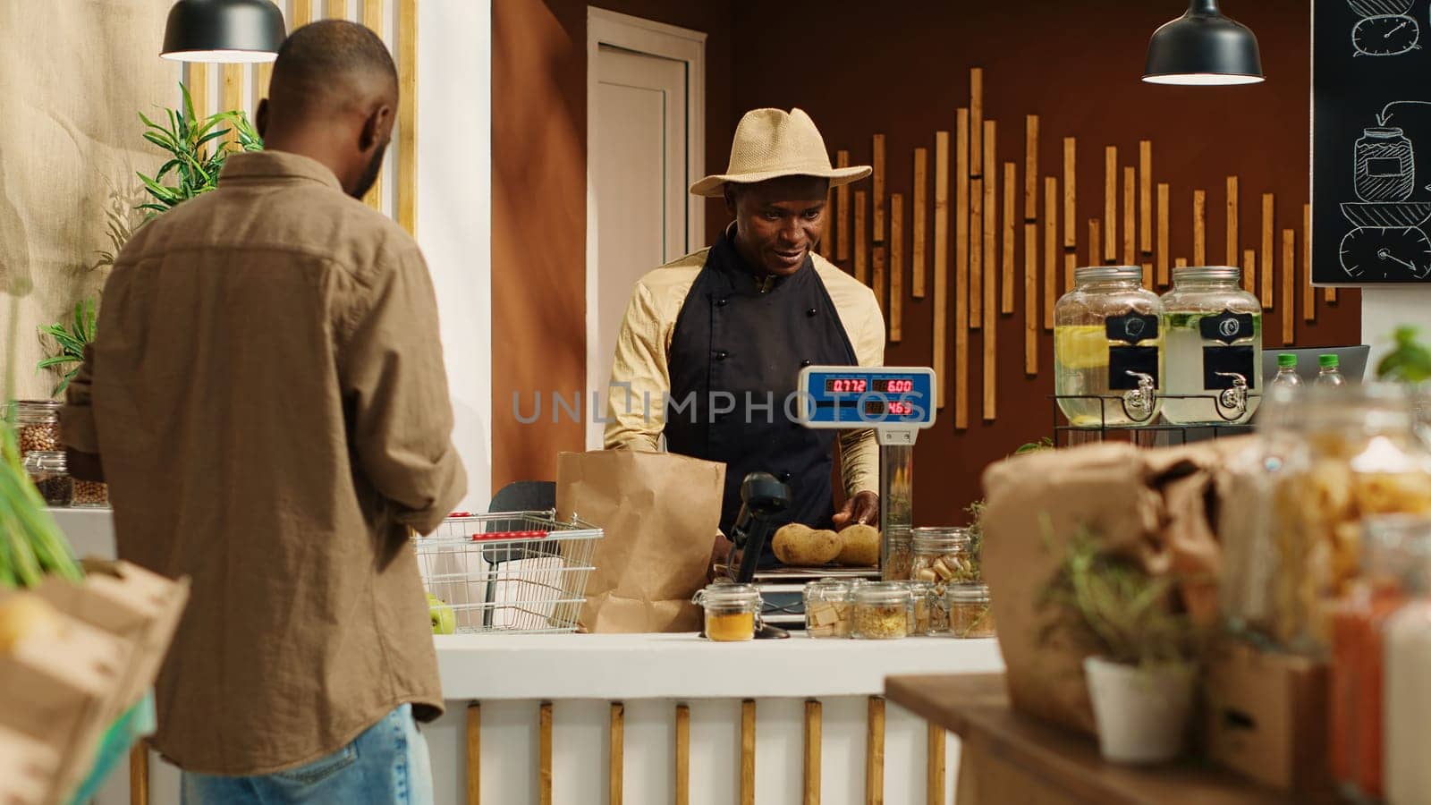 Vendor weighting goods for customer at cash register in store, supports sustainable lifestyle by buying ethically sourced produce. Client choosing fresh fruits and veggies from supermarket. Camera 1.