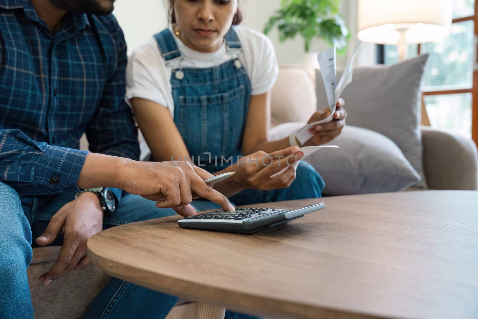 Indian Couple Managing Finances at Home, Paying Bills, and Planning Budget Together in a Modern Living Room by itchaznong