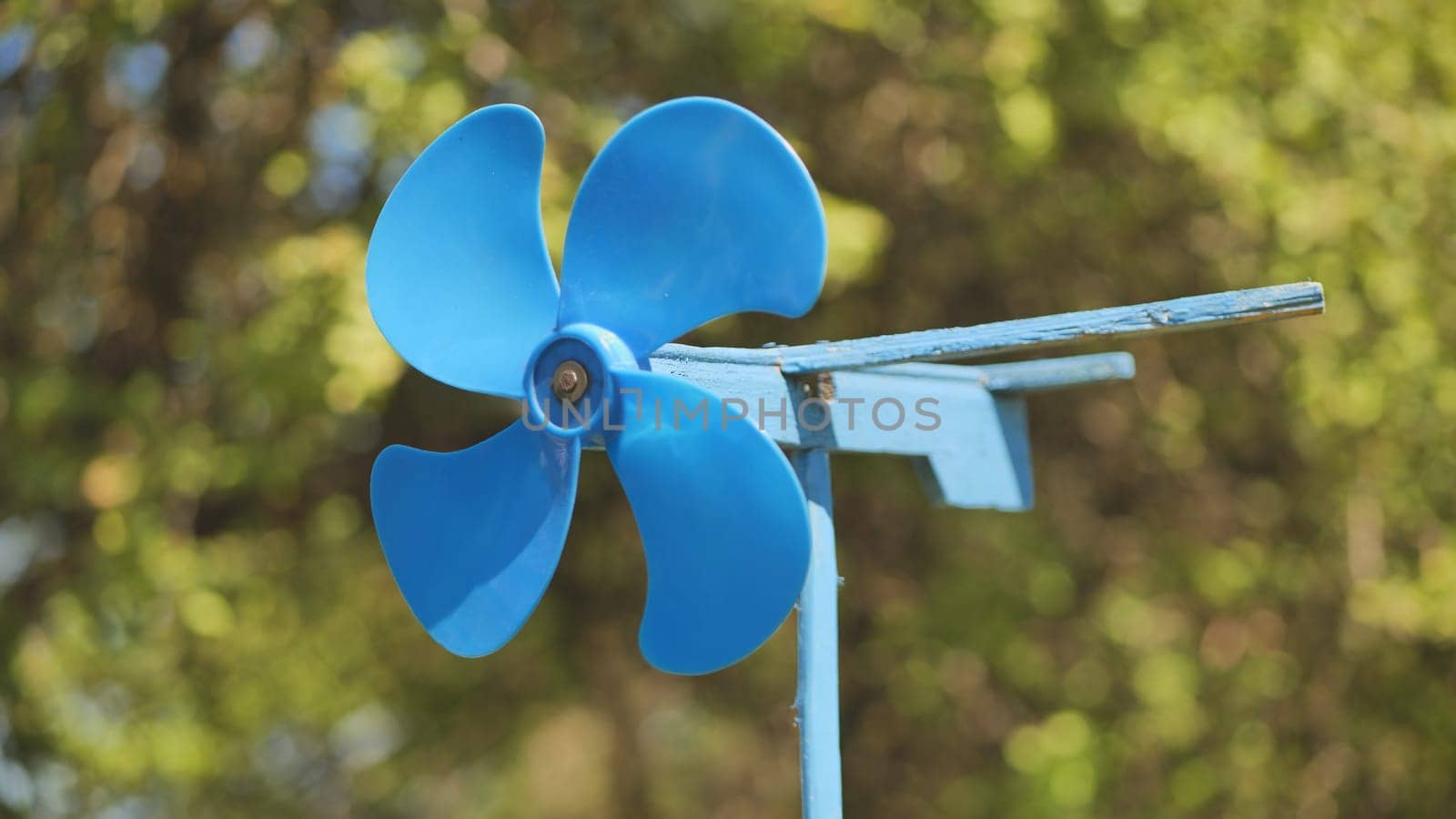 A blue vane weathervane spins in the wind in the summer