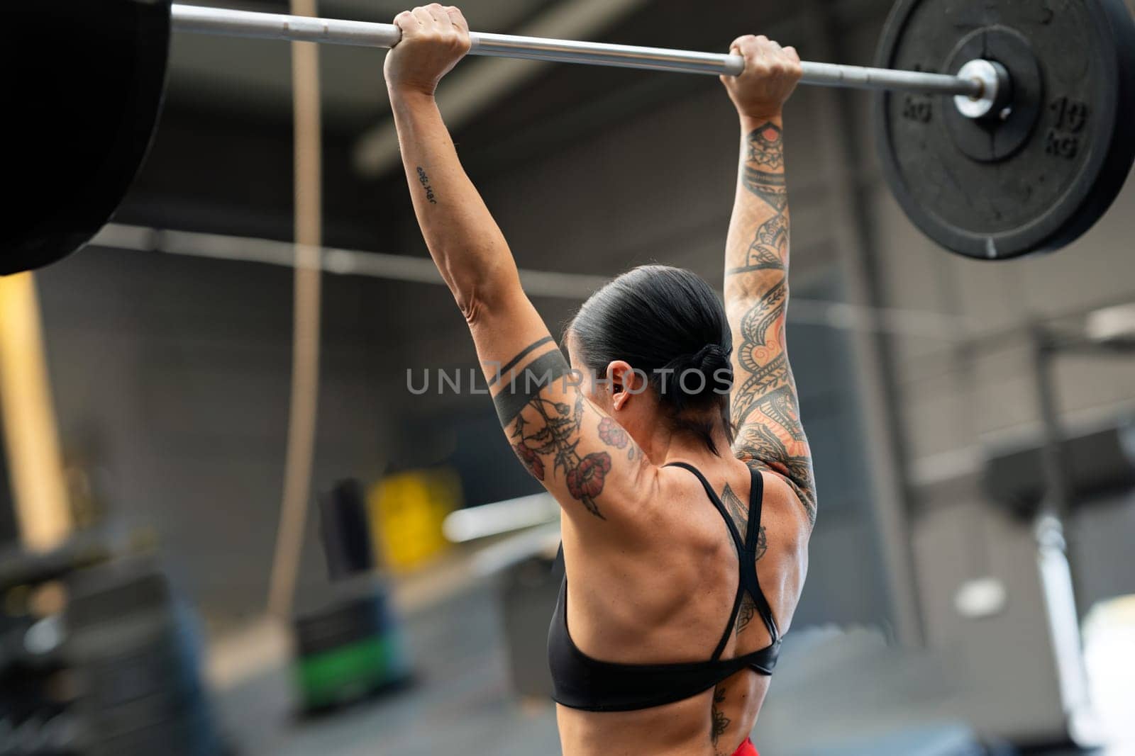 Rear view of a strong fit woman lifting barbell in a cross training gym