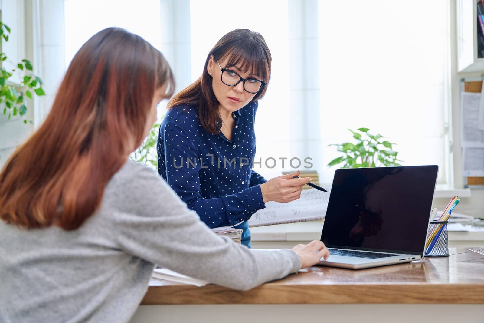 Female teacher mentor teaching young teenage girl student using laptop computer by VH-studio