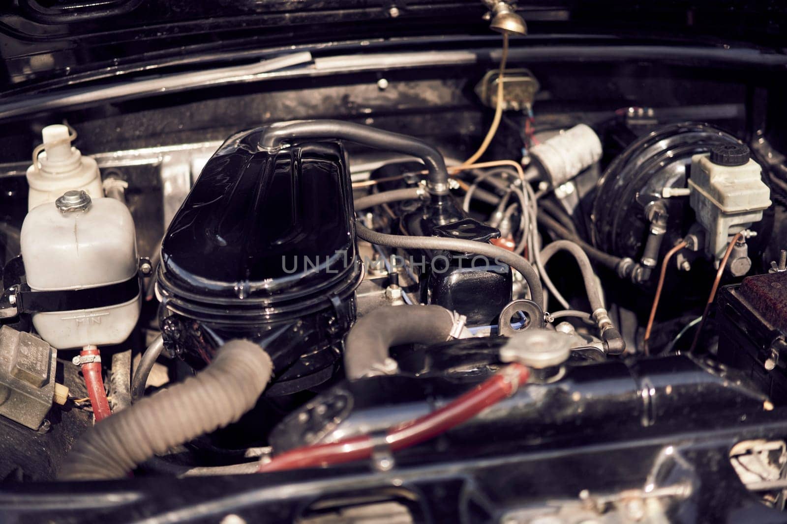 A detailed view of a classic car engine shows mechanical parts and wiring components under the hood