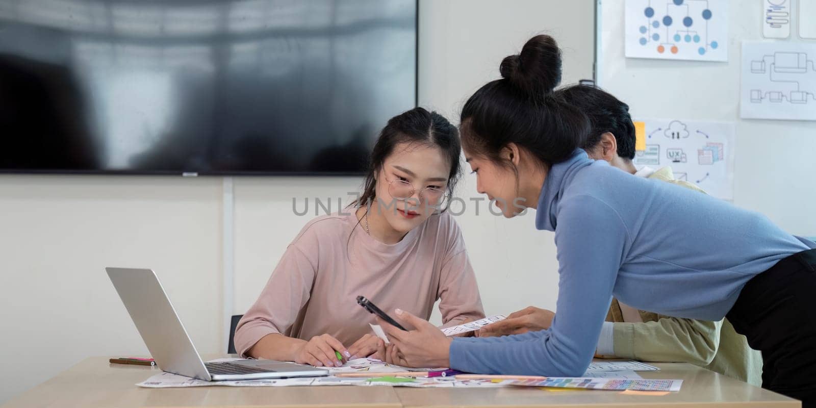 UX developer and UI designer collaborating in a modern office, brainstorming ideas with digital devices and design prototypes.