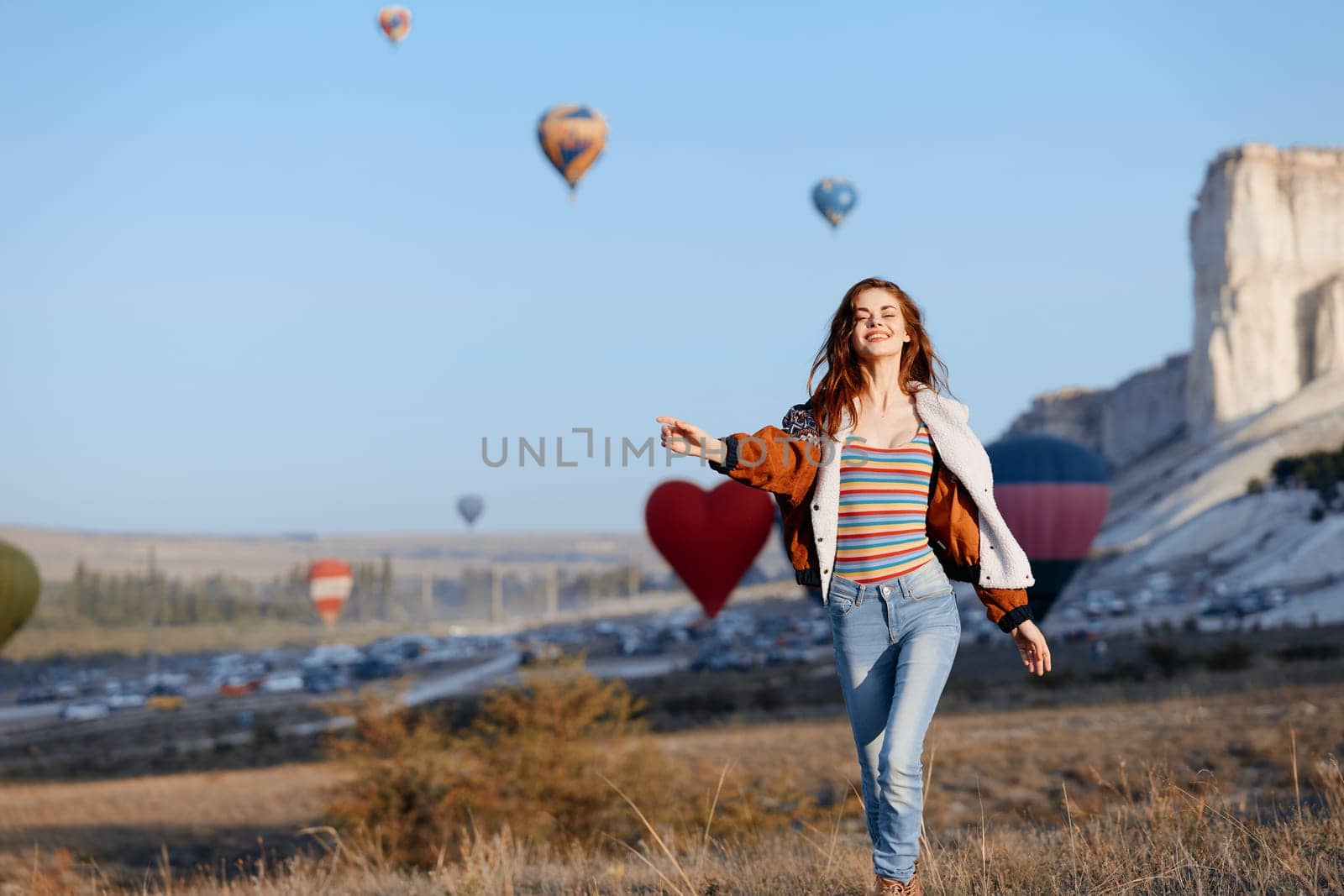 vibrant hot air balloons soar behind a stylish woman in striped shirt and jeans