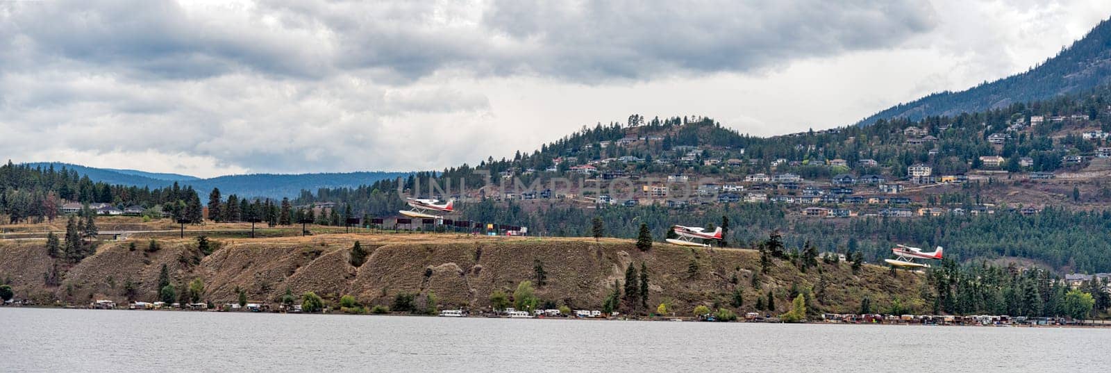 A small seaplane taking off a water surface on overcast day in Okanagan valley