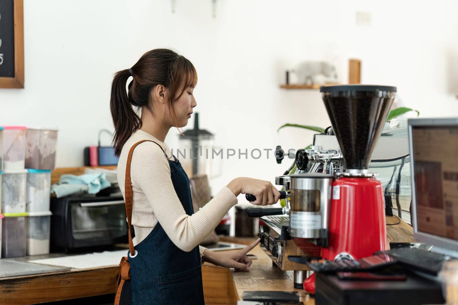 Small Business Owner Portrait woman in a blue apron is making coffee at a coffee shop by itchaznong