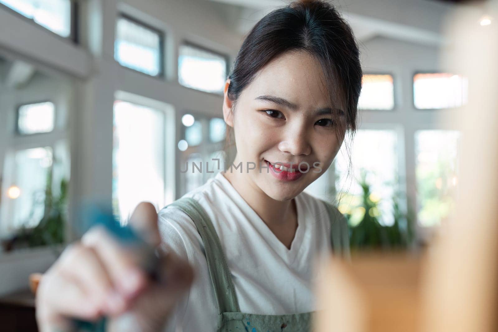 Young Woman Enjoying Creative Hobby Indoors - Smiling Female Engaged in Artistic Activity at Home - Bright and Airy Room with Natural Light - Focus on Leisure and Personal Development by itchaznong