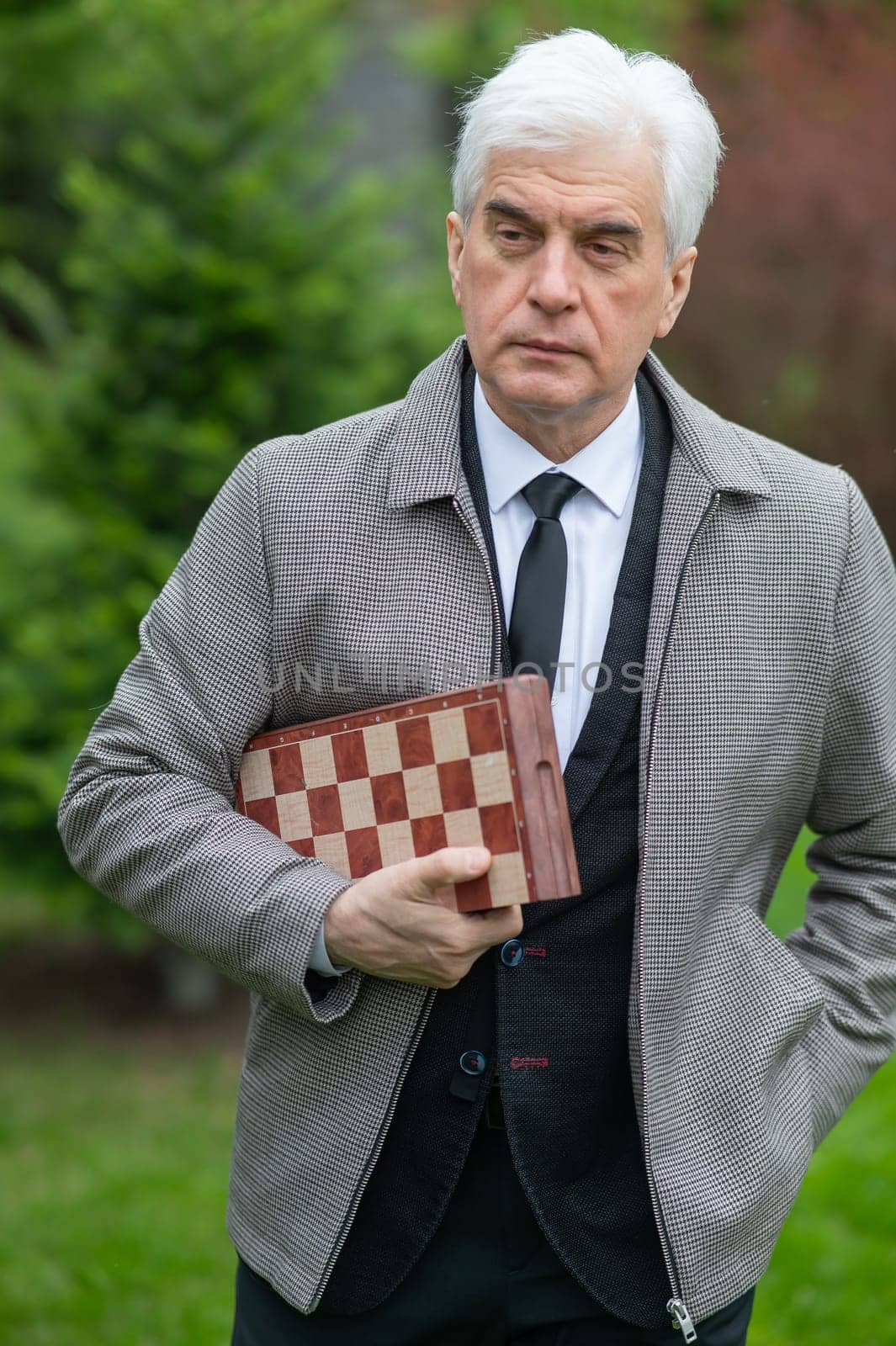 Elderly Caucasian man holding chess outdoors. Vertical photo. by mrwed54