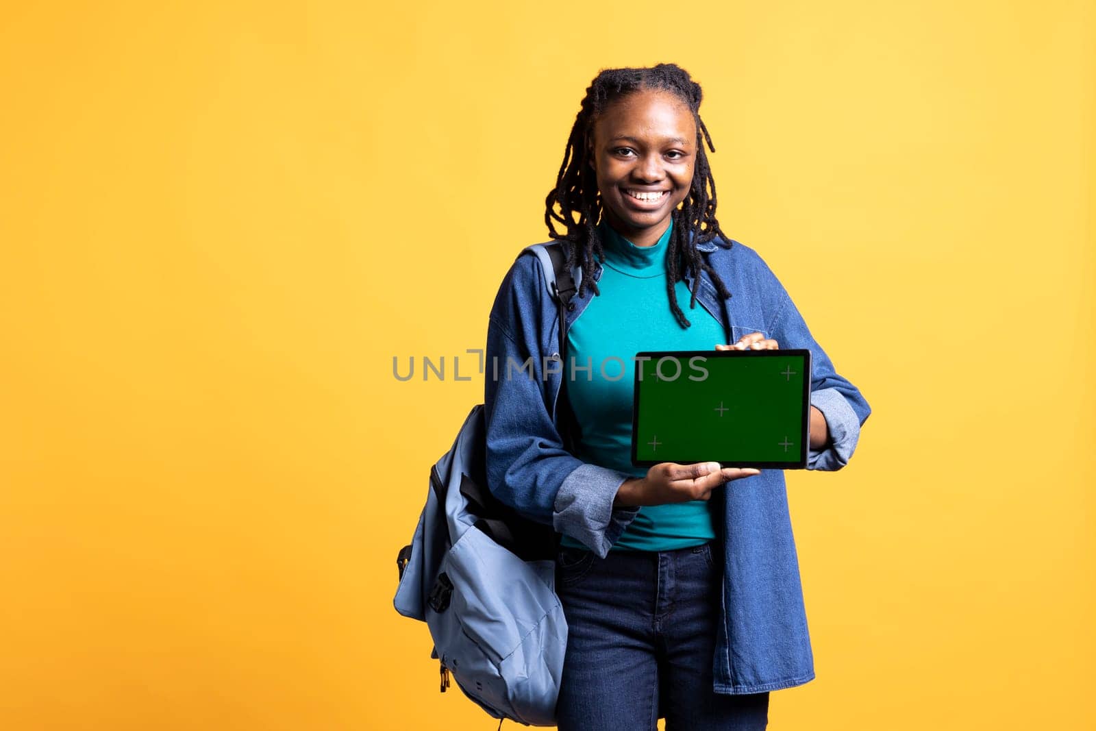 Happy african american girl laughing while presenting tablet with isolated screen display, studio background. Cheerful BIPOC person has fun during promotion for chroma key device