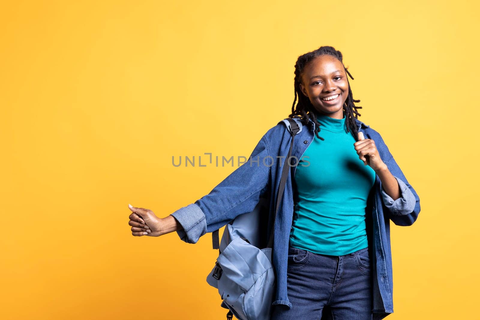 Smiling african american teenager having fun, dancing on rhythm, enjoying leisure time. Jolly BIPOC girl entertaining herself doing funky movements on music, studio background