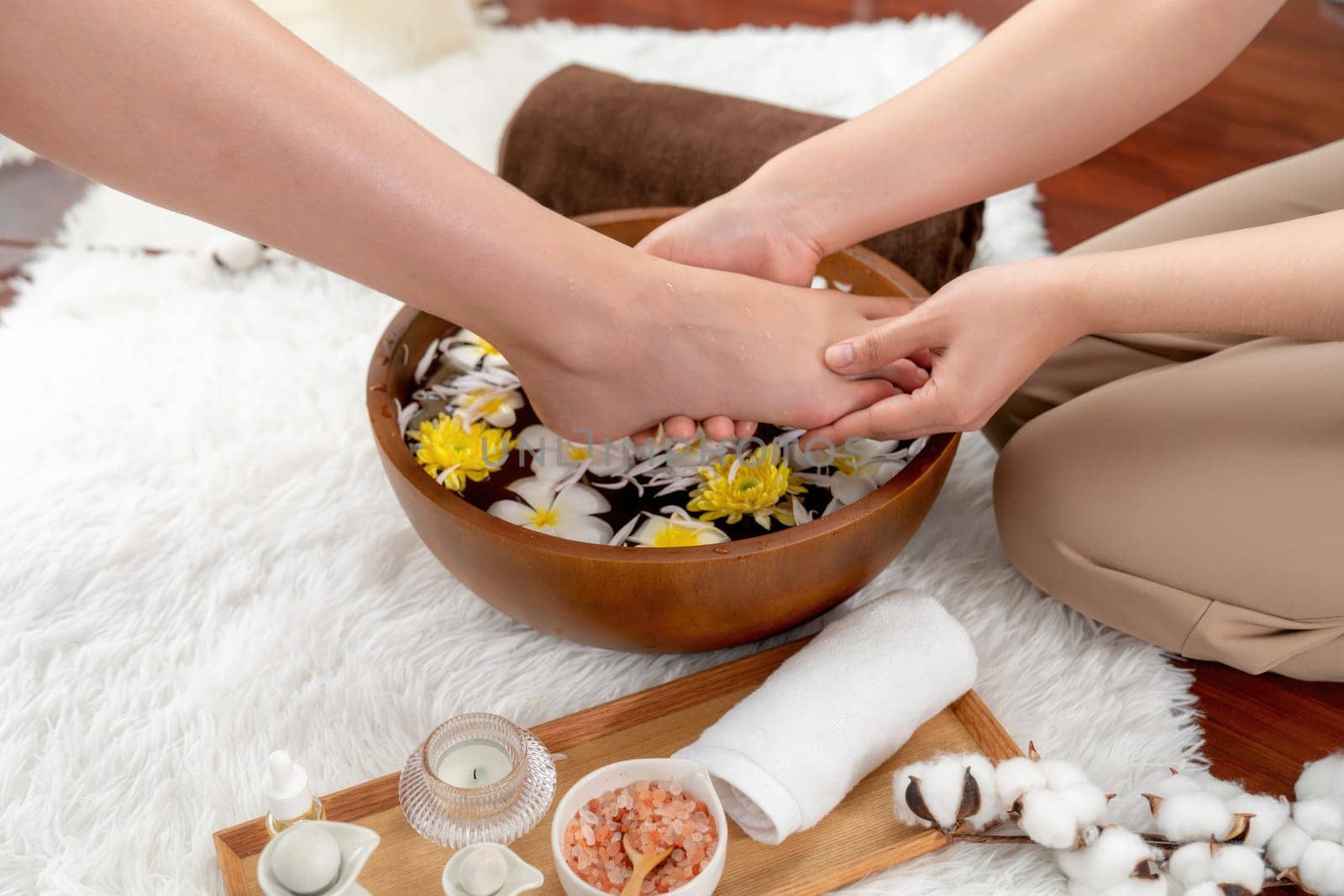 Woman indulges in blissful foot massage at luxurious spa salon while masseur give reflexology therapy in gentle day light ambiance resort or hotel foot spa. Quiescent