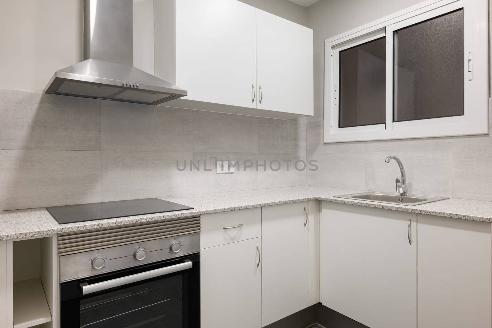 Bright and contemporary kitchen with sleek white cabinets, stainless steel appliances, and clean countertops. Includes electric stove, oven, and minimalist design.
