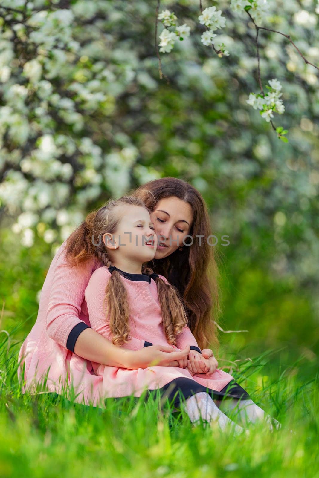 mother and daughter walk through a blooming garden by zokov