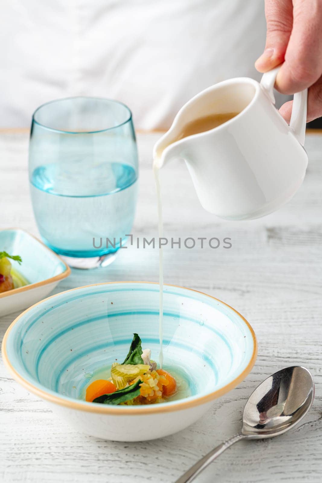 Fish soup with vegetables on white wooden table