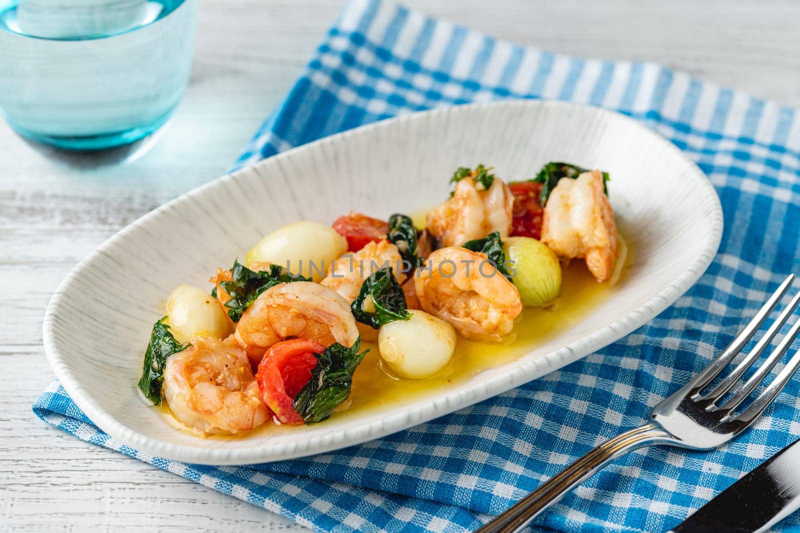 Appetizer with shrimps, onions and tomatoes on a white porcelain plate