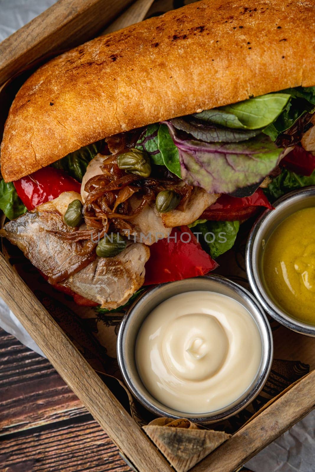 Steak sandwich with sauces and french fries on wooden table