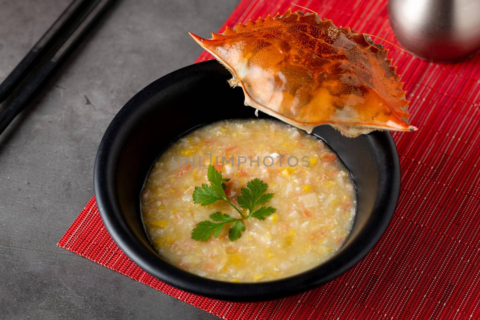 Crab soup in black porcelain plate on gray stone table by Sonat