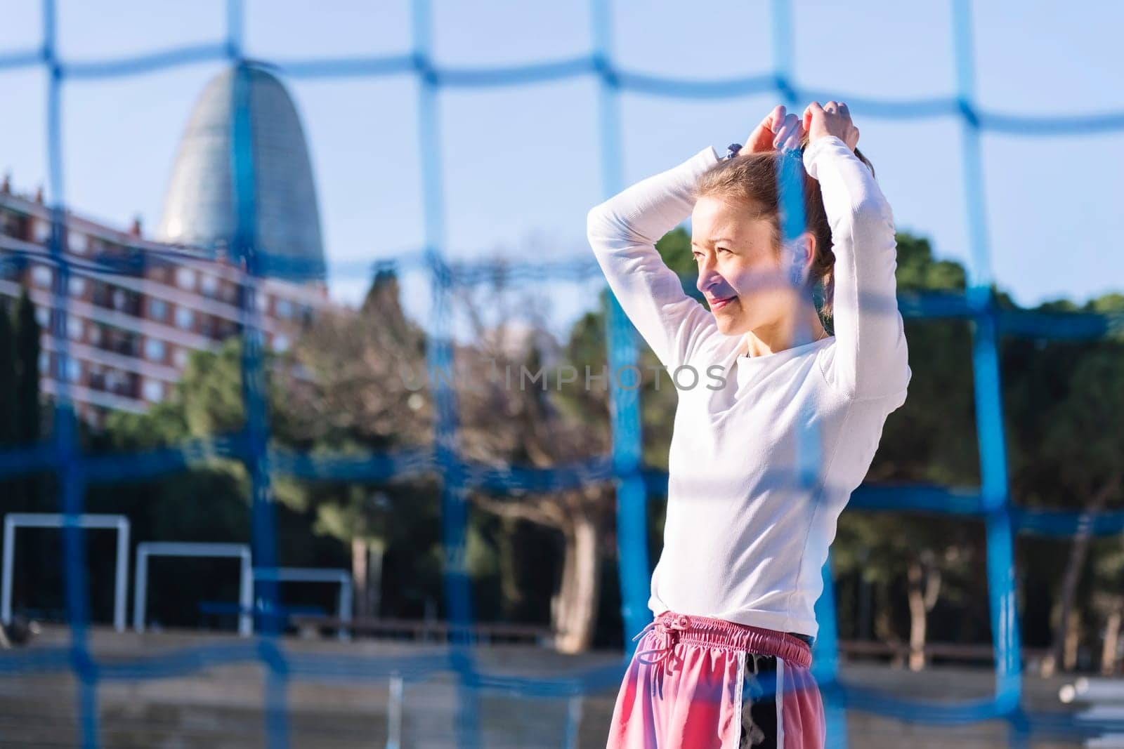 female soccer player making a ponytail to play on an urban football court, concept of sport and active lifestyle, copy space for text