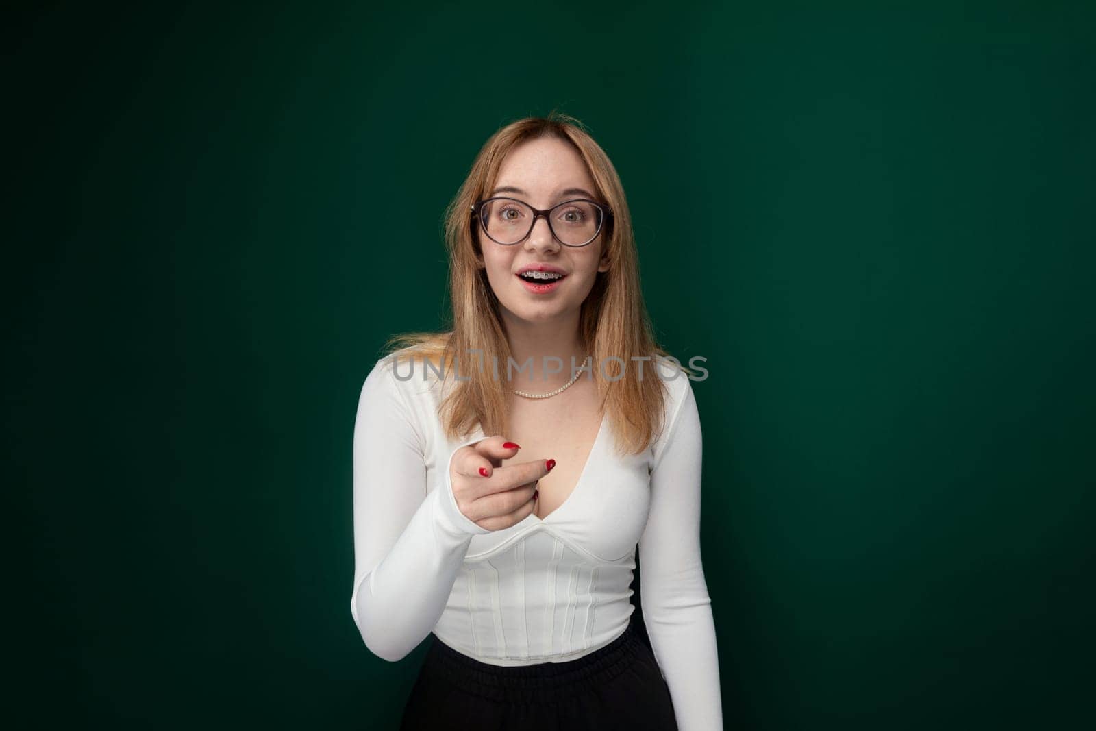 A woman wearing glasses and a white shirt is standing outdoors. She appears confident and focused, looking ahead. Her white shirt complements her simple yet stylish appearance.