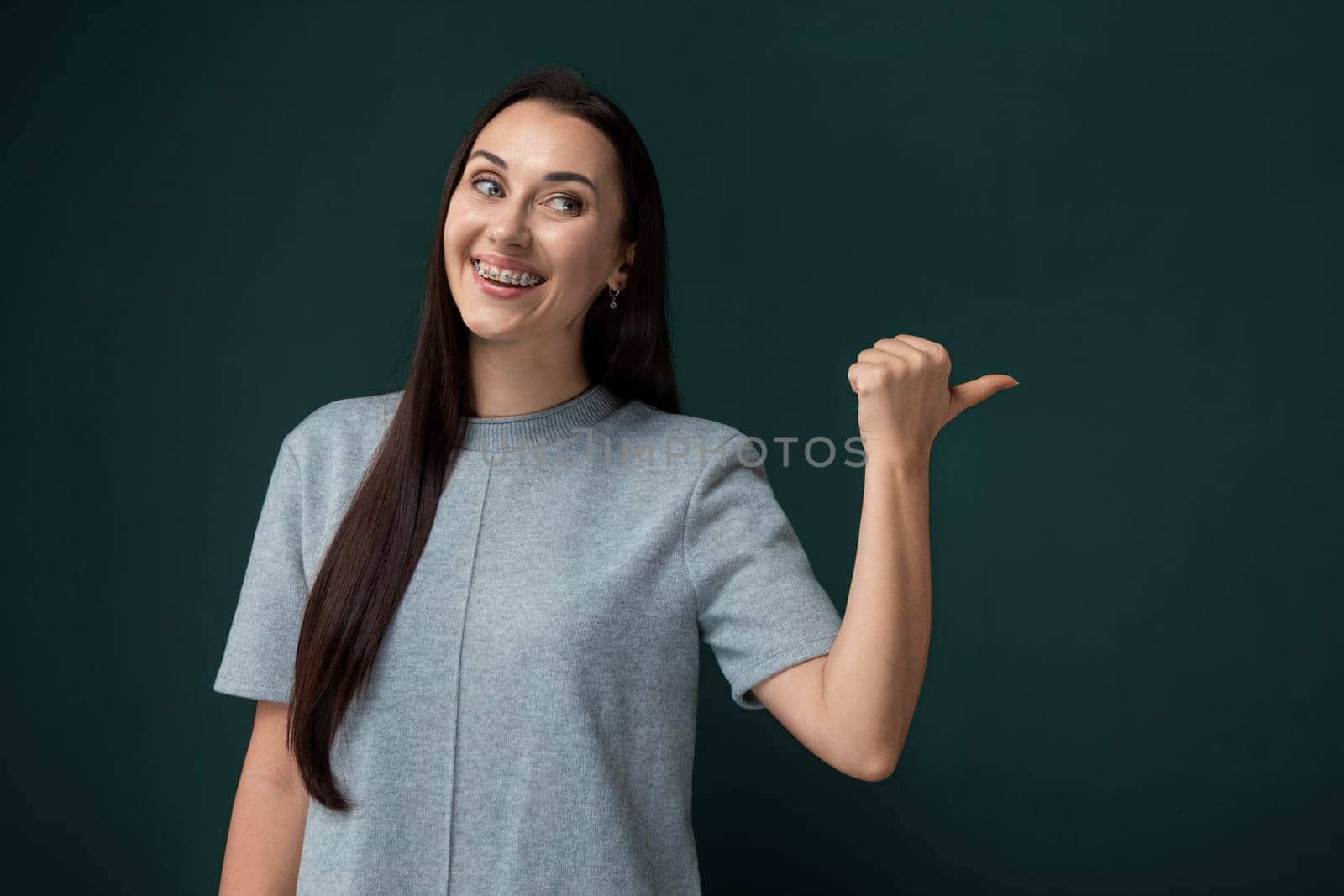 A woman is pointing with her finger, indicating something off-camera. She appears to be directing attention towards a certain object or area, her body language showing a clear focus on whatever she is pointing at.