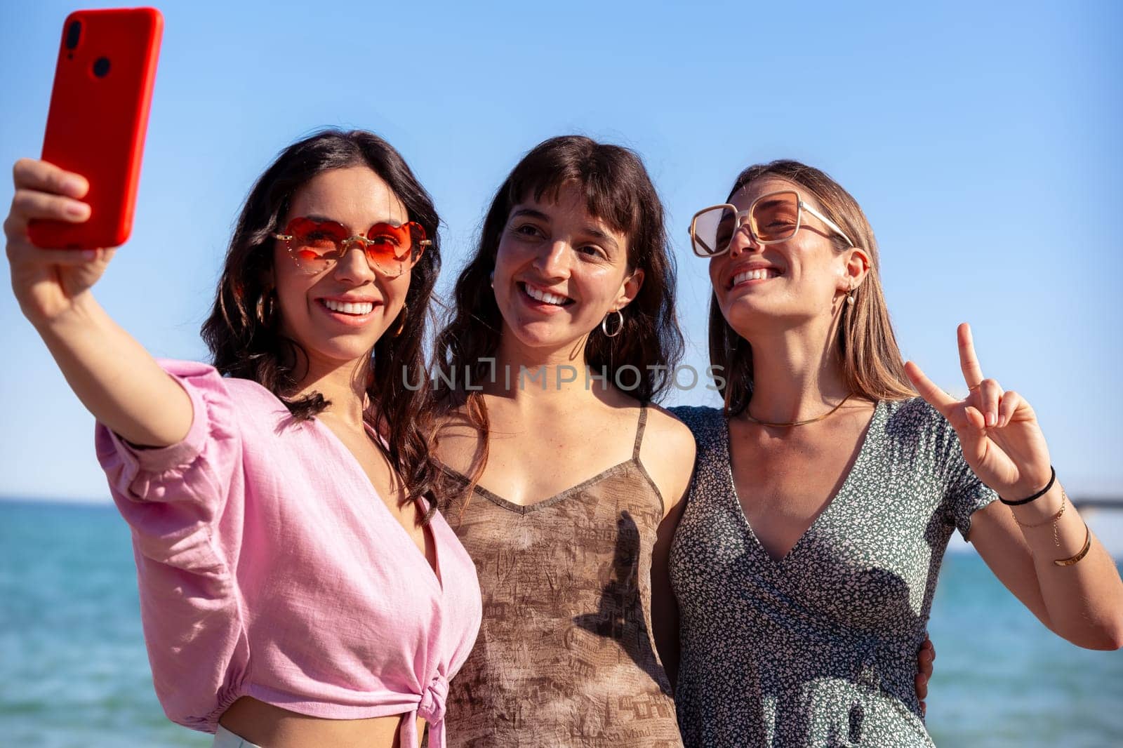 Group of smiling multiethnic women enjoying vacation. Beautiful and cheerful girls of generation z pose for a photo with a mobile phone.