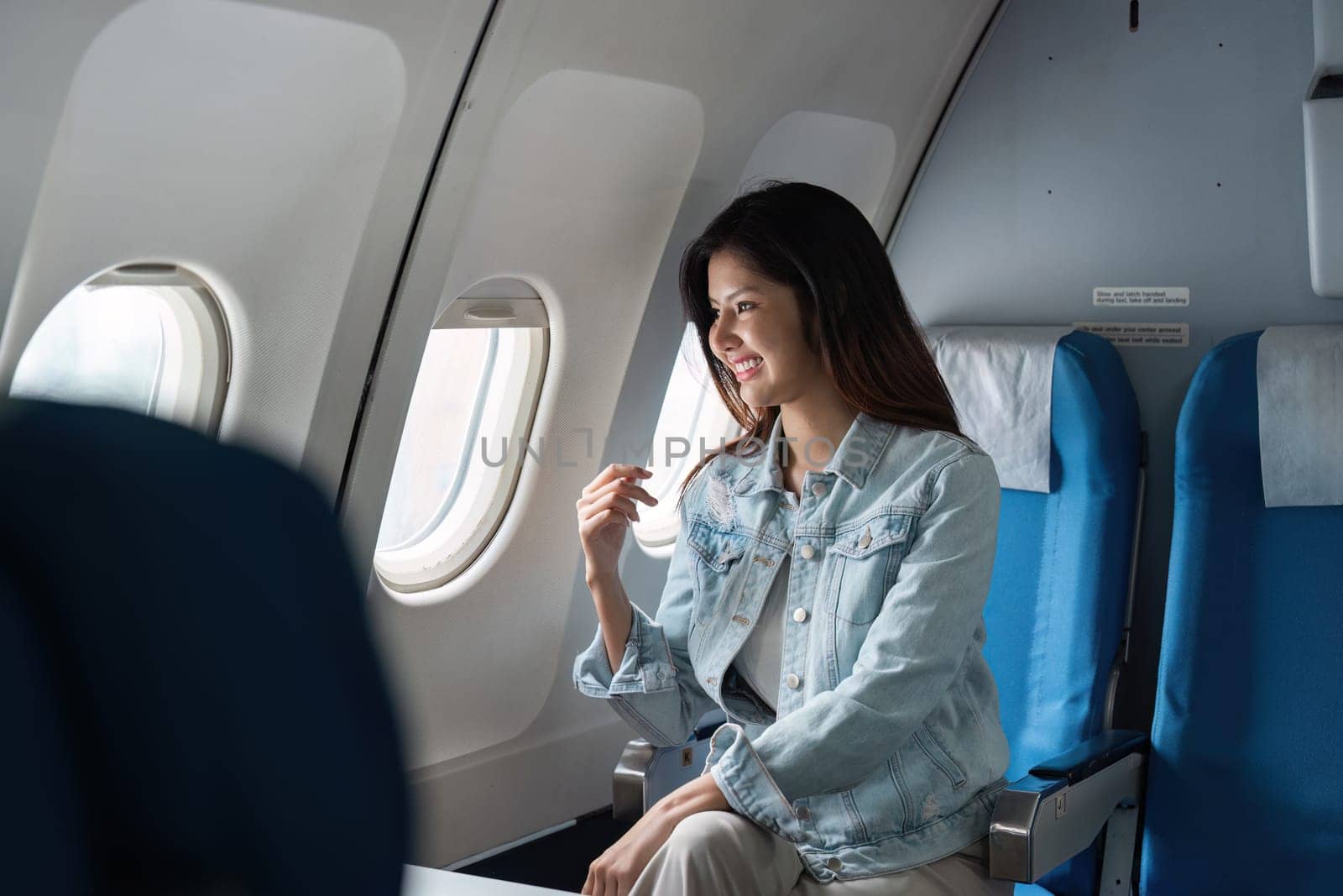 A businesswoman sitting comfortably in a modern business airplane, enjoying the view through large windows.