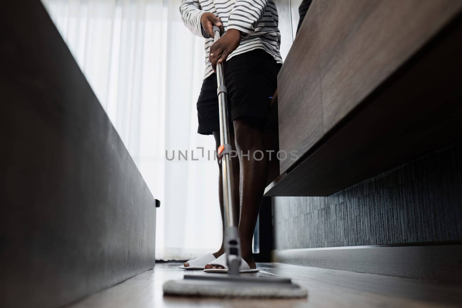 Close-up of a person mopping the floor in a modern home, showcasing cleaning tools and a tidy living environment.