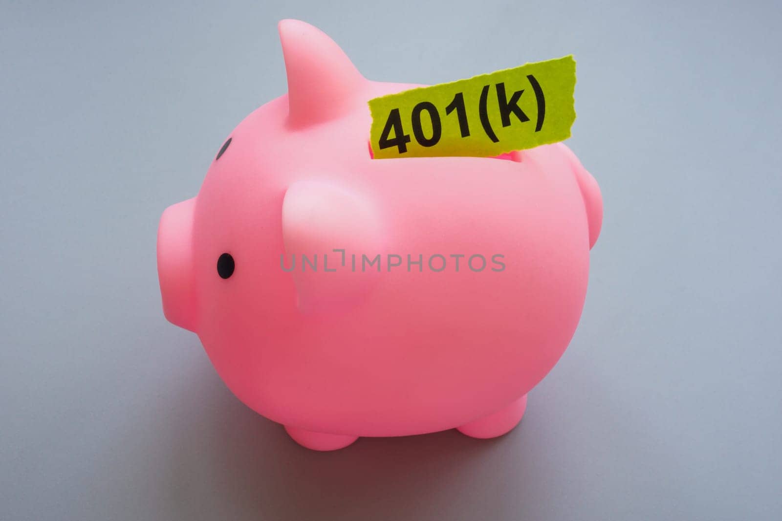 Pink piggy bank with inserted word 401k about pension plan.