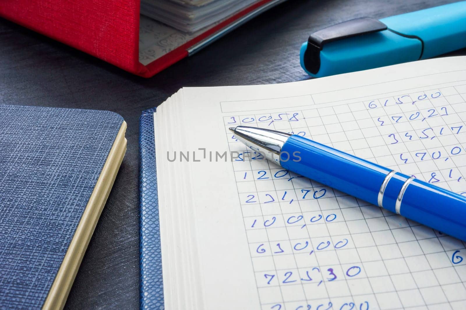 An open ledger with financial records, pen and a folder.