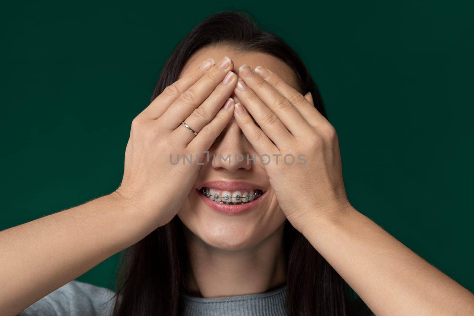 A woman is shown covering her eyes with her hands, possibly indicating surprise, fear, or to shield herself from a bright light. Her hands are positioned over her eyes in a protective gesture.